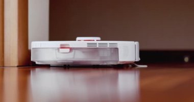 Ahşap zemininde karaciğer olan akıllı robot süpürgesi. Robot elektrikli süpürge daireyi otomatik olarak temizliyor. 4K ağır çekim 100 fps, ProRes 422, 10 bit