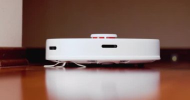 Ahşap zemininde karaciğer olan akıllı robot süpürgesi. Robot elektrikli süpürge daireyi otomatik olarak temizliyor. 4K ağır çekim 100 fps, ProRes 422, 10 bit