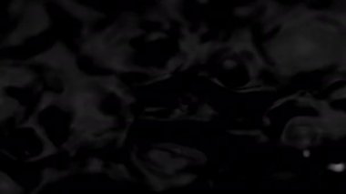 Splashes and drops on the surface of the liquid. Abstract Black Background Water vibration. 4K slow motion 100 fps, ProRes 422, 10 bit