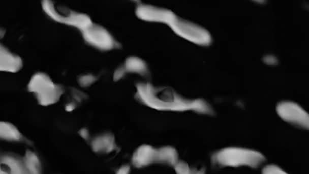 Spritzer und Tropfen auf der Oberfläche der Flüssigkeit. Abstrakter schwarzer Hintergrund Wasservibration. 4K Zeitlupe 100 fps, ProRes 422, 10 bit — Stockvideo