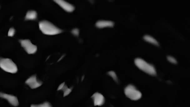 Salpicaduras y gotas en la superficie del líquido. Fondo negro abstracto Vibración del agua. 4K cámara lenta 100 fps, ProRes 422, 10 bit — Vídeo de stock