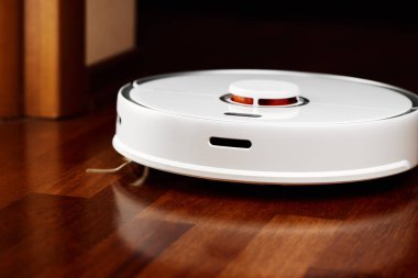Ahşap zeminde akıllı robot elektrikli süpürge. Robot elektrikli süpürge daireyi belli bir zamanda otomatik olarak temizliyor. Akıllı ev