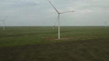Enerji üretimi için güçlü rüzgar türbini çiftliğinin havadan görüntüsü. Rüzgar güç türbinleri sürdürülebilir gelişim için temiz yenilenebilir enerji üretiyor. Alternatif enerji. 4K