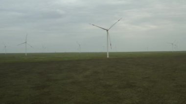 Enerji üretimi için güçlü rüzgar türbini çiftliğinin havadan görüntüsü. Rüzgar güç türbinleri sürdürülebilir gelişim için temiz yenilenebilir enerji üretiyor. Alternatif enerji. 4K