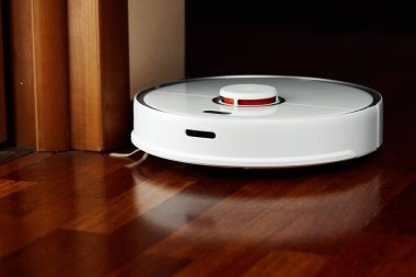 Ahşap zeminde akıllı robot elektrikli süpürge. Robot elektrikli süpürge daireyi belli bir zamanda otomatik olarak temizliyor. Akıllı ev