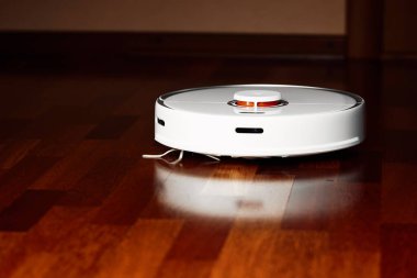 Ahşap zeminde akıllı robot elektrikli süpürge. Robot elektrikli süpürge daireyi belli bir zamanda otomatik olarak temizliyor. Akıllı ev