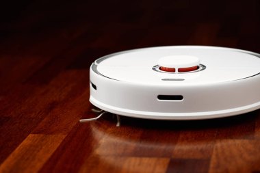 Ahşap zeminde akıllı robot elektrikli süpürge. Robot elektrikli süpürge daireyi belli bir zamanda otomatik olarak temizliyor. Akıllı ev