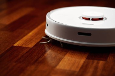 Ahşap zeminde akıllı robot elektrikli süpürge. Robot elektrikli süpürge daireyi belli bir zamanda otomatik olarak temizliyor. Akıllı ev