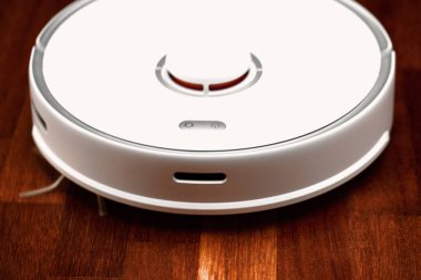 Ahşap zeminde akıllı robot elektrikli süpürge. Robot elektrikli süpürge daireyi belli bir zamanda otomatik olarak temizliyor. Akıllı ev