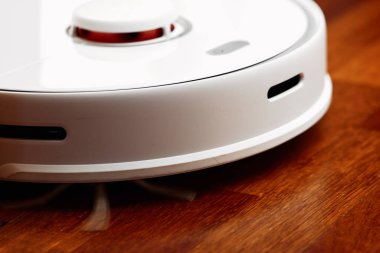 Ahşap zeminde akıllı robot elektrikli süpürge. Robot elektrikli süpürge daireyi belli bir zamanda otomatik olarak temizliyor. Akıllı ev