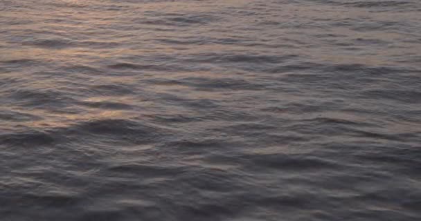 Water oppervlak bij zonsondergang. oppervlak van het in donker water bij zonsondergang licht. Zonsondergang reflecterend. Trage beweging 100 fps video, ProRes 422, ongesorteerd C-LOG3 10 bit — Stockvideo