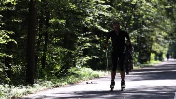 Training an athlete on the roller skaters. Biathlon ride on the roller skis with ski poles. Training between seasons on Roller skis in the park. Slow motion 120 fps video. 28.08.2021, Moscow Region — Stock Video