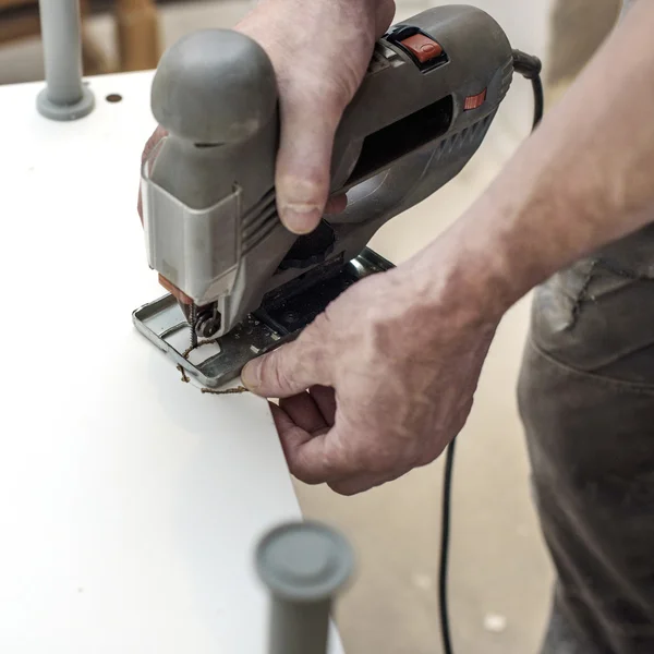 Carpenter works with an electric jigsaw — Stock Photo, Image