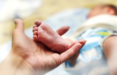 Yeni doğan çocuğun annesinin elinde küçük bacak