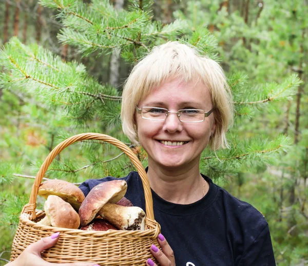 Счастливая женщина средних лет держит корзину с съедобными грибами — стоковое фото