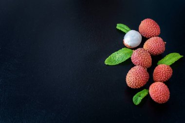 Siyah arkaplan üzerinde taze liçi meyvesi, üst görünüm fotoğrafı, metin için kopyalama alanı.