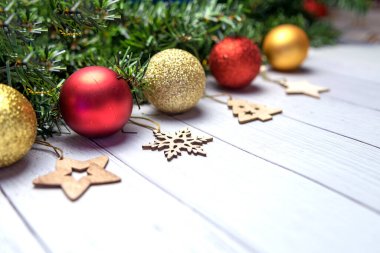 Noel kompozisyonu köknar dalları, altın ve kırmızı balonlar, tahta oyuncaklar beyaz ahşap arka planda