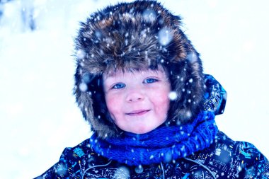 Şapka kulaklığı takmış küçük bir çocuğun güzel, gülümseyen yüzü. Büyük göz. Kameraya bakıyorum. Yakından..