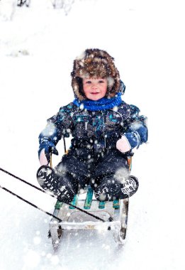 Kar kızağında kürk şapkalı güzel çocuk..