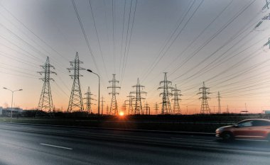 Yüksek voltajlı bir elektrik kulesinin siluetleri gündoğumu ve gökyüzünün arka planına karşı. Güç hattı