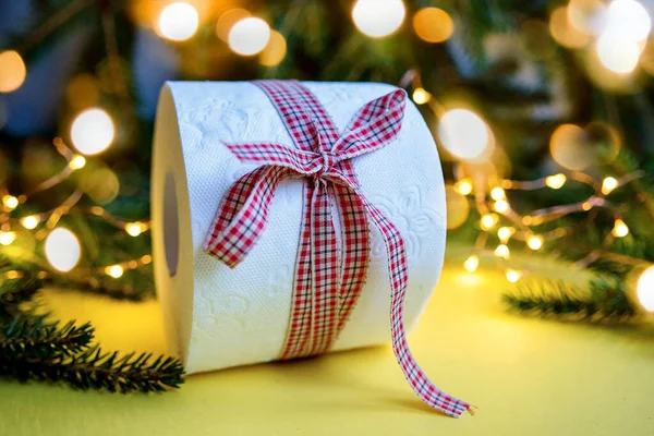 Toilettenpapierrolle Als Weihnachtsgeschenk Neben Weihnachtsbaum Und Weihnachtsbeleuchtung Auf Gelbem Hintergrund — Stockfoto