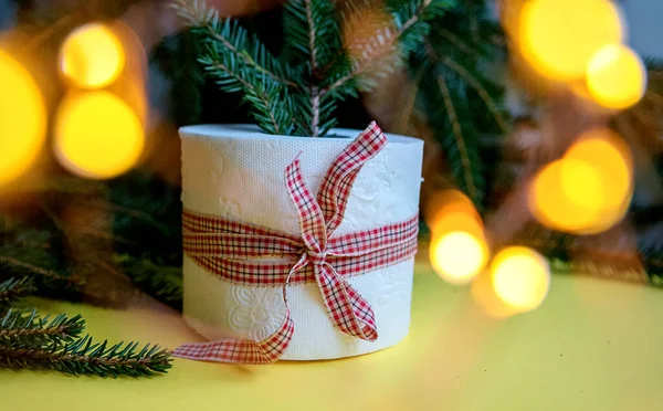 Toilettenpapierrolle Als Weihnachtsgeschenk Neben Weihnachtsbaum Und Weihnachtsbeleuchtung Auf Gelbem Hintergrund — Stockfoto