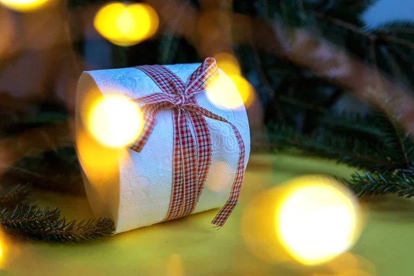 Toilettenpapierrolle Als Weihnachtsgeschenk Neben Weihnachtsbaum Und Weihnachtsbeleuchtung Auf Gelbem Hintergrund — Stockfoto