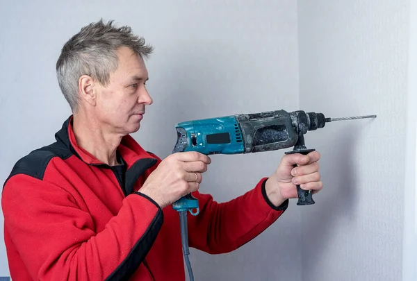 Portrait of a man with a drill in his hands. A man during a pandemic makes home repairs himself.