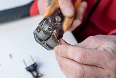 Ev hobisi. Beyaz bir arka planda elektrik kablosu üzerinde çalışan bir striptizci ve tel yalıtım aleti tutan beyaz bir adamın yakın çekimi.