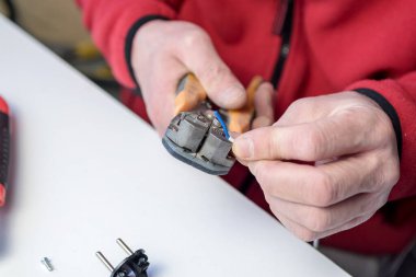 Ev hobisi. Beyaz bir arka planda elektrik kablosu üzerinde çalışan bir striptizci ve tel yalıtım aleti tutan beyaz bir adamın yakın çekimi.