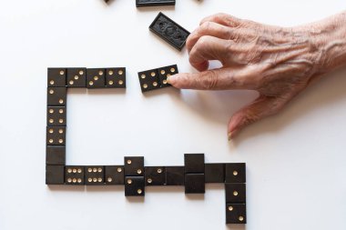 Eğlenceli bir domino oyunu için aile eğlencesi. Yaşlı bir kadının eli masaya domino taşını koyar..