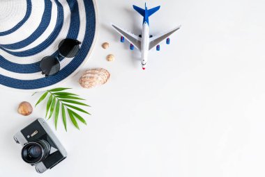Yaz tatilleri için şeyler: kamera, deniz kabuğu, uçak, güneş gözlüğü, şapka, palmiye ağacı. Seyahat ve tatil zamanı. Beyaz arka plan, üst manzara. Boşluğu kopyala