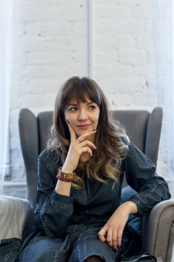 Duygusal açıdan güzel, genç bir esmer evdeki oturma odasında bir sandalyede oturuyor.