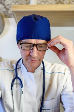 Dost canlısı bir yaşlı doktor klinikteki yaşlı kadın hastaya reçete yazıyor..