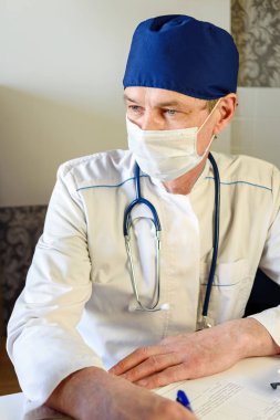 Dost canlısı bir yaşlı doktor klinikteki yaşlı kadın hastaya reçete yazıyor..