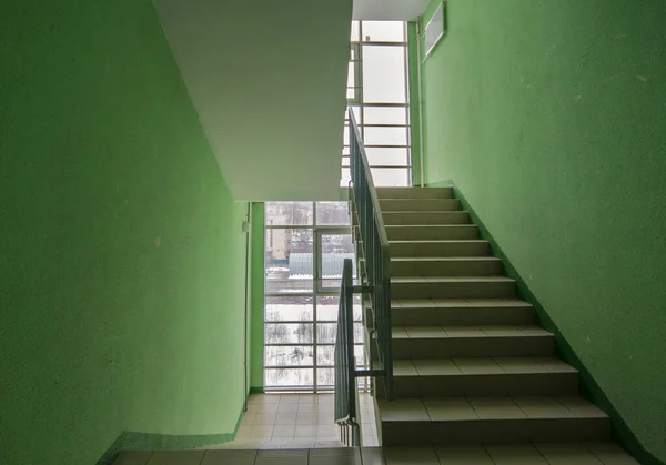 Stairs in a residential building. A wide-angle view of a modern flight of stairs against a green wall. Stairs in the modern lobby of the house