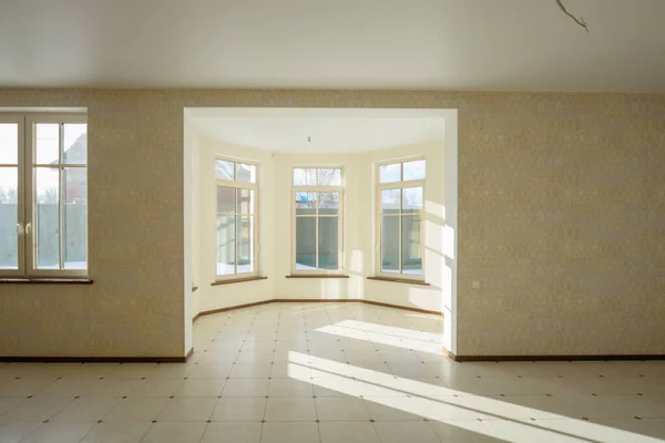 Interior of the empty living room in the cottage with tiled floors and large windows. Sunny interior.