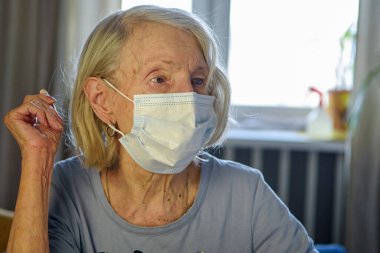 Evde 85 yıllık maskeli yaşlı bir büyükanne doktorun tavsiyelerini dinliyor. Yaşlılar için sağlık hizmeti kavramı