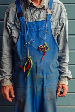 Boynunda acı biber demeti olan kirli tulum giymiş bir işçi. Keyfin yerinde.