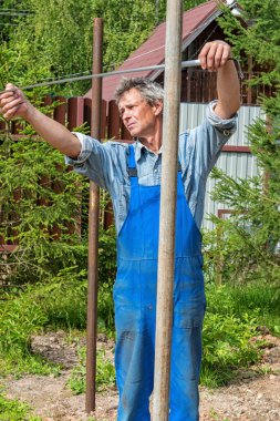 Doğada gerçek bir inşaat alanında mezurası olan bir erkek müteahhit. Bir mezura ile iletiler arasındaki mesafeyi ölçer