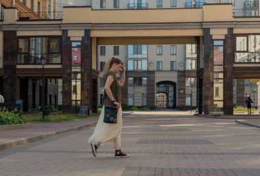 Uzun etekli, çantalı, caddeden karşıya geçen güzel bir genç kadın, başka tarafa bakıyor. Kız yazın St. Petersburg 'da yürüyor..