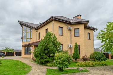 Köy evi. Evin etrafında yeşil çimenler ve ağaçlar var.