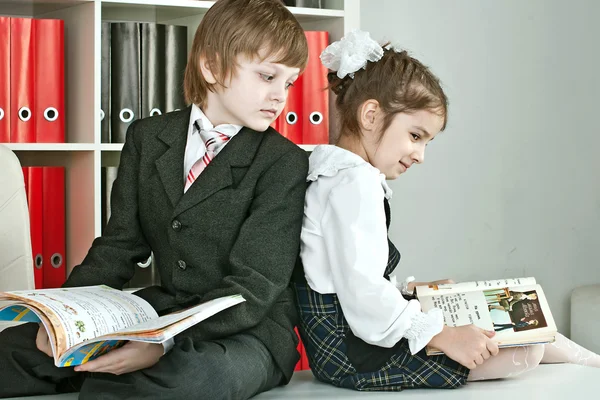 Garçon et fille assis sur un bureau à l'école — Photo