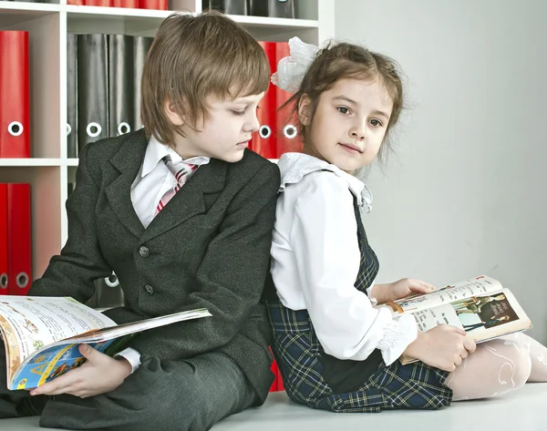 Boy and girl sitting on a desk at school — Stock Photo, Image