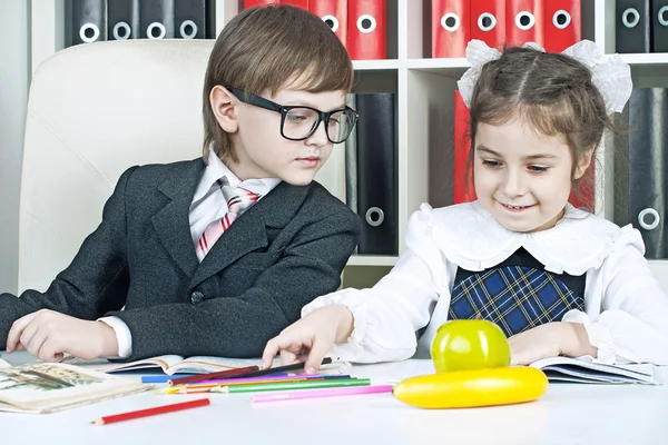 Pojke och flicka sitter vid ett bord i skolbarn med böcker — Stockfoto