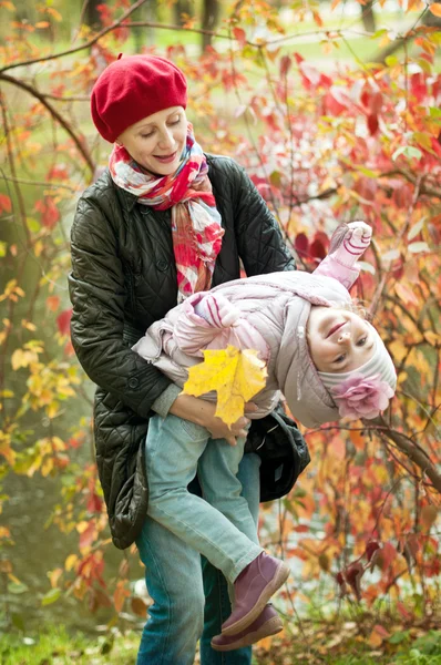 Dívka a matka se schovávají za stromem v podzimním parku — Stock fotografie