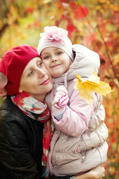 Dívka a matka se schovávají za stromem v podzimním parku — Stock fotografie