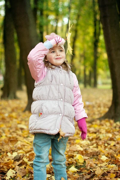 Dívka si hraje s podzimní listí v parku — Stock fotografie