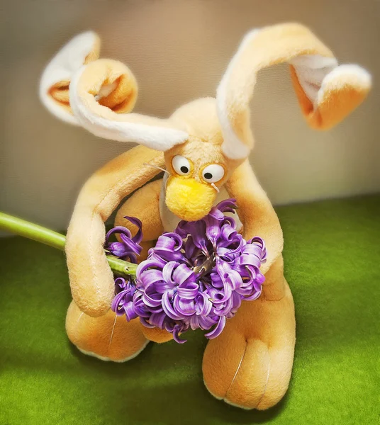 Gökyüzüne karşı bir çiçek tutan Paskalya kompozisyon oyuncak tavşanı — Stok fotoğraf