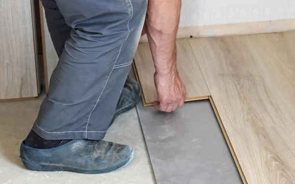 Male carpenter puts the laminate — Stock Photo, Image